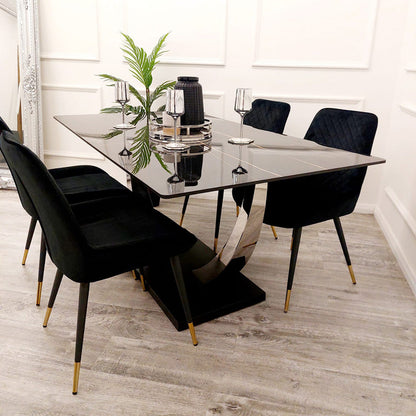 Dining table set with black chairs and a plant in a modern interior.